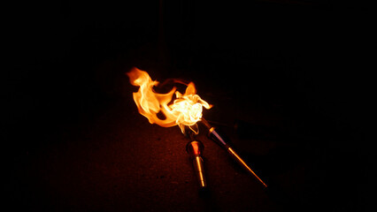Closeup shot of two burning juggling torches on a dark background