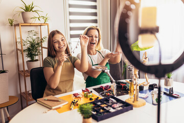 Mother and daughter accessories designers making handmade jewelry in studio workshop and recording video. Fashion, creativity and handmade concept.