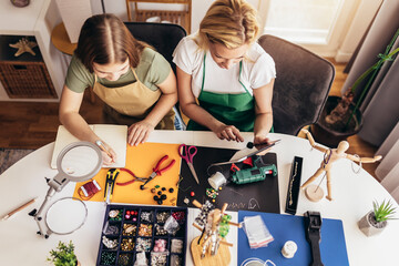 Mother and daughter accessories designers making handmade jewelry in studio workshop. Fashion,...