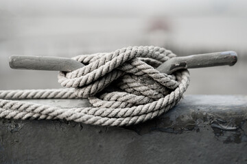 Closeup shot of a rope tied in a knot on a metal pipe in black and white