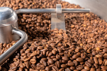 Coffee roaster machine at coffee roasting process. Mixing coffee grain. Roaster and cooling professional machines and fresh brown coffee beans close up at factory. Food and drink background for cafe.