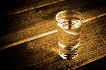 Transparent glass vodka shot on black bar. Empty copy space dark sad alcoholism background. Long way out of addiction. Loneliness and the long process out of it. Problem with alcohol.