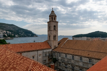 Fototapeta premium Saint Dominic Church Bell Tower and red rooftop against blue sky with clouds in the old town of Dubrovnik, Croatia.