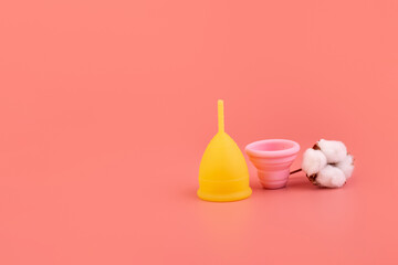 Silicone pink and yellow menstrual cup with cotton. Women's health and alternative hygiene on a pink background. eco-friendly, Alternative reusable product for female hygiene. Minimalism soft, organic