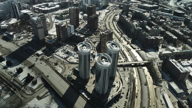 Three tall modern buildings standing in the middle of a dirty city.