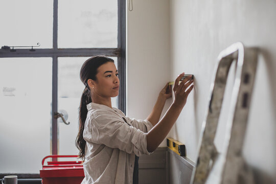 Mid adult female measuring wall for home renovations