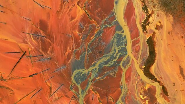 Acid river flowing from industrial copper zinc mine pollutes environment. Orange toxic soil is contaminated with heavy metals from industrial plant. Aerial drone view
