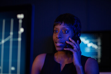 Female stockbroker trading late at night on a phonecall