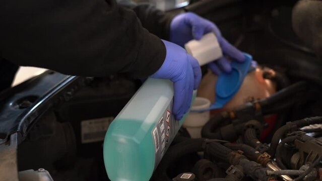 A technician fills a vehicle washer bottle (no logos only COSHH symbols)