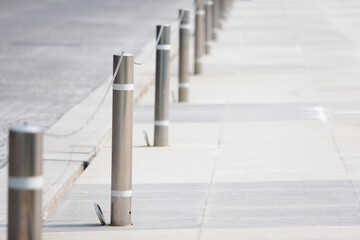 Obraz premium stainless steel bollards with chain on footpath. silver metal bollards.