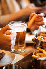 Holding glass mug of fresh cool beer above the dinner table