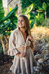 Attractive young fair-skinned woman stands near banana trees in tropical park