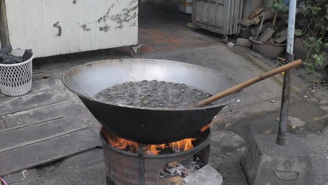 black snails boiling in a large outdoor wok cooking 