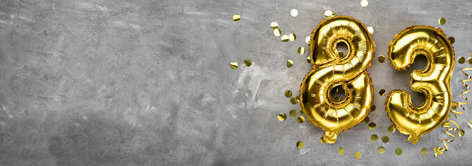 Yellow foil balloon number, number eighty three on a concrete background. Greeting card with the inscription 83. Anniversary concept. for anniversary, birthday, new year celebration. banner,