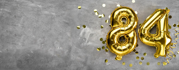 Yellow foil balloon number, number eighty four on a concrete background. Greeting card with the inscription 84. Anniversary concept. for anniversary, birthday, new year celebration. banner,