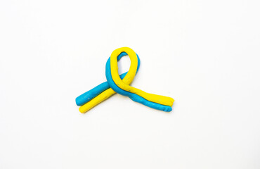blue-yellow ribbon with plasticine as a symbol of Ukraine on a white background, War in Ukraine.