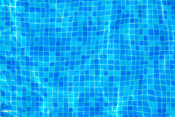 Clear water surface, ripple water in tiled swimming pool with sun reflection