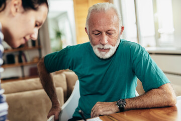 Young doctor during home visit senior man