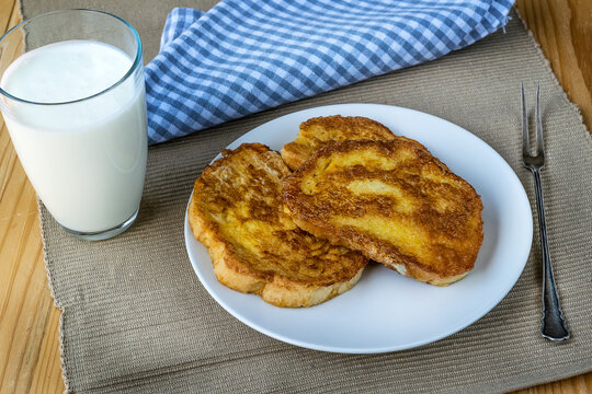 French toast - Przenice - slices of bread soaked in beaten eggs and milk and fried, with a glas of yogurt on a wooden table. Eggy bread, Bombay toast, German toast, gypsy toast or poor knightsles