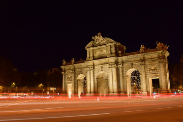 Fototapeta na wymiar The Puerta de Alcala in Madrid at night. With flashes and lights of cars passing by. Famous monument of the Spanish capital.