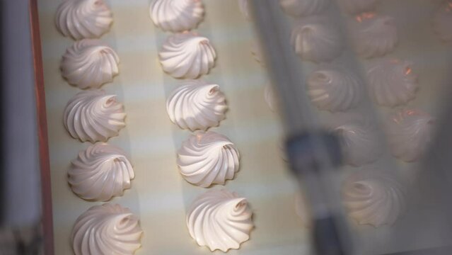 Freshly-made vanilla zephyr desserts on the conveyor line. Marshmallow manufacturing at modern food factory. Close up. Top view.