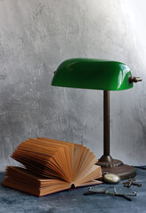 Simple composition still life with vintage lamp and book on a desk. Retro styled objects close up photo. 