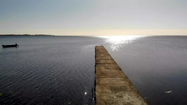 Aerial view flying over a boat bridge in the sea in Nyk&oslash;bing Bugt towards the sun.
