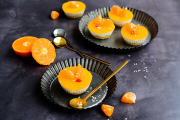 Cottage cheese dessert with tangerine jelly in the form of muffins on a dark gray background. Delicious sugar free desserts