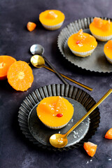 vertical composition. Curd dessert without sugar with tangerine jelly on metal plates on a dark gray background