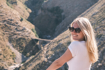 Side view portrait confident young cheerful smiling blonde woman looks into the camera wearing sunglasses against the background of nature on a sunny day. Happy girl smiles broadly