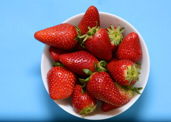 Strawberry in plate Fresh strawberry on a blue background. Top view of strawberries with leaves