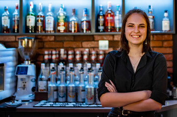 Portrait of young attractive woman bartender behind the bar counter