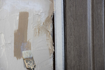 Preparing the wall for leveling with plaster. Priming a concrete wall with an old natural bristle brush.