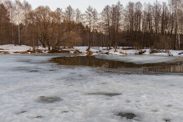 Melting ice and snow. Spring landscape, evening forest with a river. The beginning of spring....