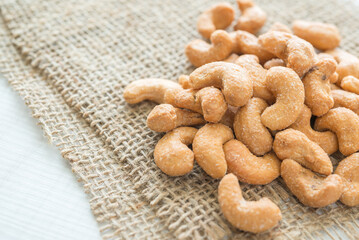 Salted cashew nuts on sackcloth background. Food and nutrition concept.