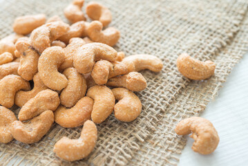 Salted cashew nuts on sackcloth background.