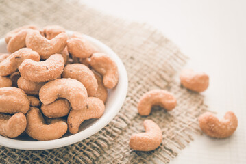 Salted cashew nuts in dessert bowl on sackcloth background. Food concept.