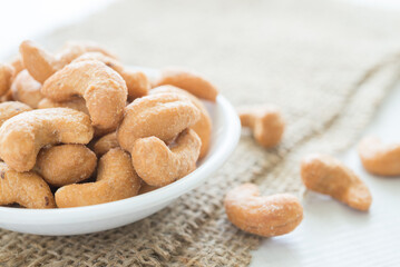 Salted cashew nuts in dessert bowl on sackcloth background. Food and nutrition concept.