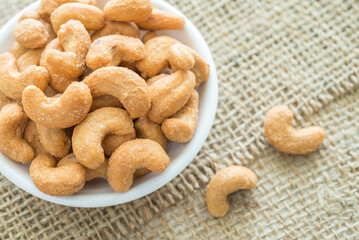 Salted cashew nuts in dessert bowl on sackcloth background. Food concept.