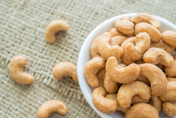 Salted cashew nuts in dessert bowl on sackcloth background.
