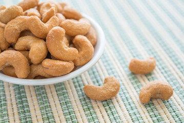 Salted cashew nuts in dessert bowl on Japanese cooking mat. Food concept.