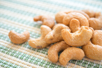 Close up salted cashew nuts on Japanese cooking mat background. Food concept.