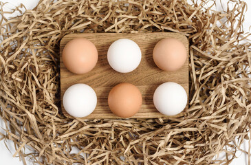 Natural chicken eggs on a wooden stand on brown shredded paper packaging Easter concept, zero waste, eco friendly