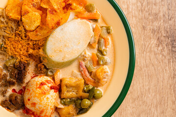 Lontong sayur or vegetable rice cake is an Indonesian traditional rice dish made of pieces of lontong served in coconut milk soup with shredded chayote, tempeh, tofu, hard-boiled egg, sambal, rendang