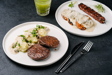 Mashed potatoes with plant-based patties and vegetarian vegetable skewers with sweet potatoes, cream sauce and parmesan. Dark concrete background