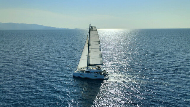 Catamaran Yacht Under Sail Moving On Open Sea At Sunset 