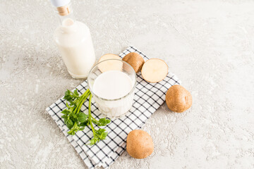 a glass of delicious healthy vegetable milk from potato tubers on a cotton napkin and a concrete background. diet food.