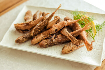 top view Fried fish smelled on the plate, served with lemon, grilled vegetables. Smelt-small sea fish