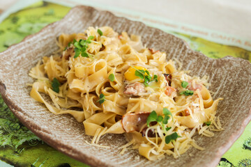 a plate of pasta carbonara with basil on a wooden table, a dish of Carbonara, a typical Italian recipe for pasta with guancale, egg and pecorino Romano cheese