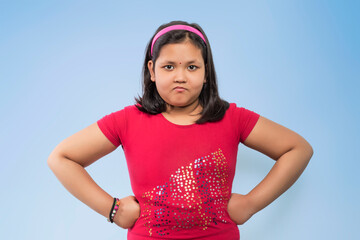 Portrait of an angry girl looking at camera isolated on a Blue background